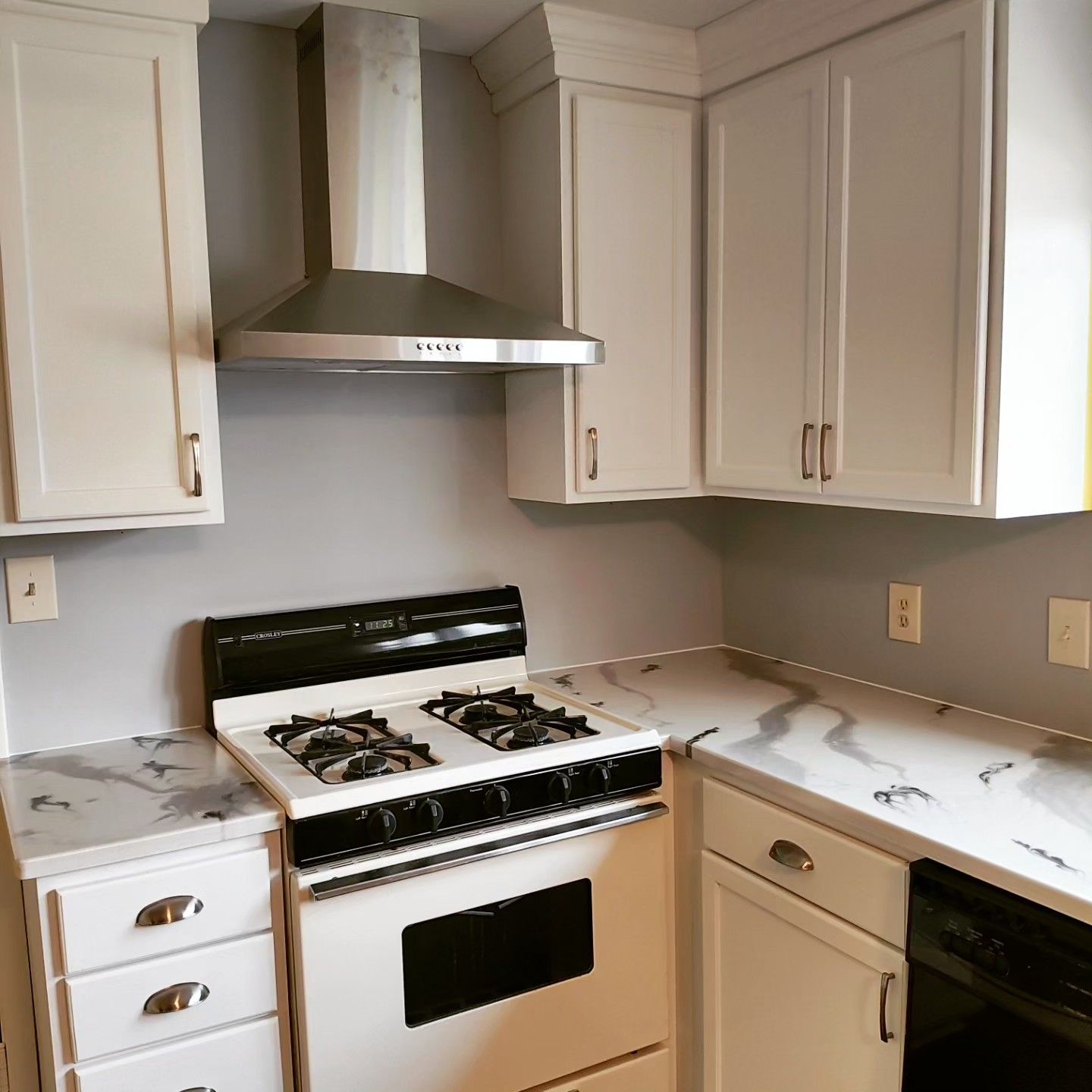 A kitchen with white cabinets and a stove top oven