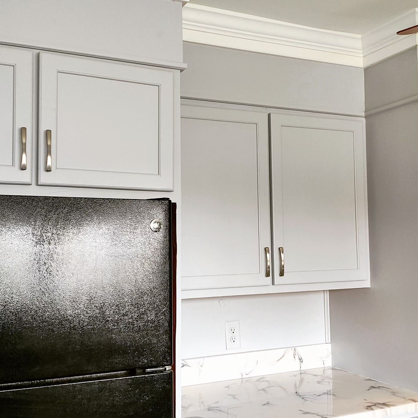 A kitchen with white cabinets and a black refrigerator