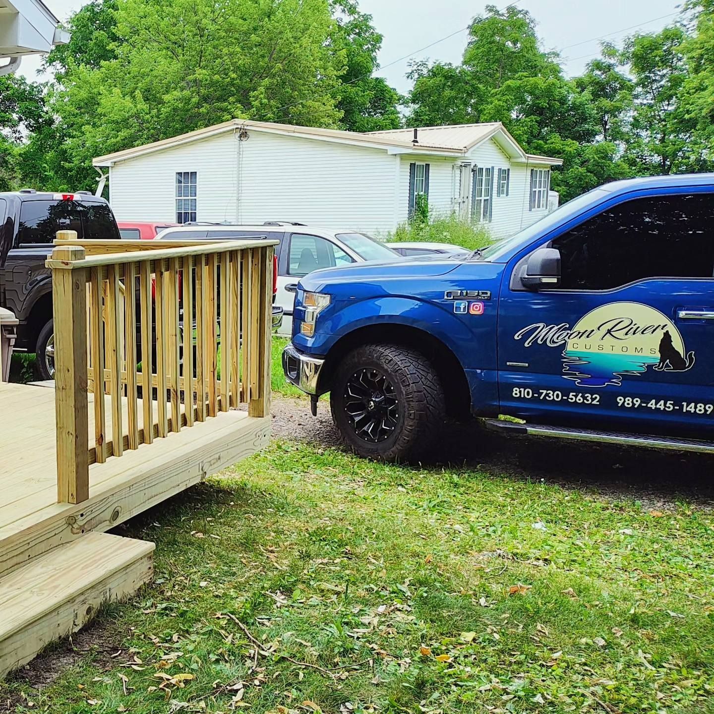 A blue truck is parked next to a wooden deck