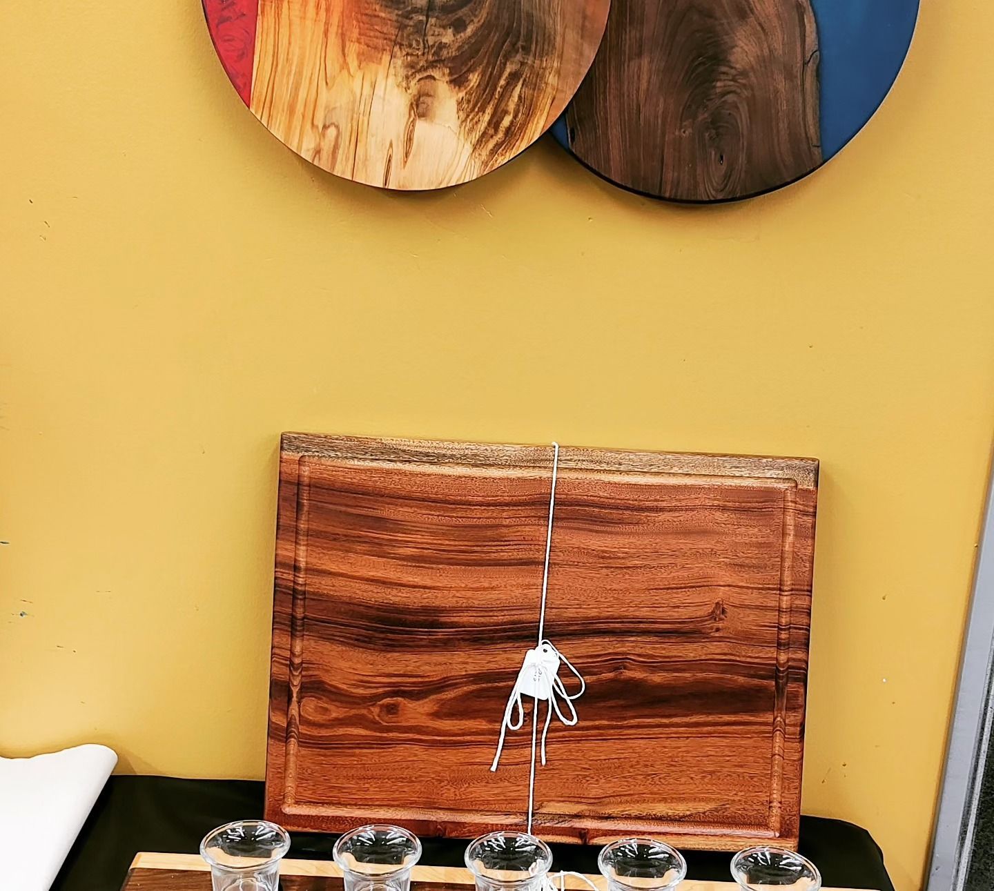 A wooden cutting board with three shot glasses on it
