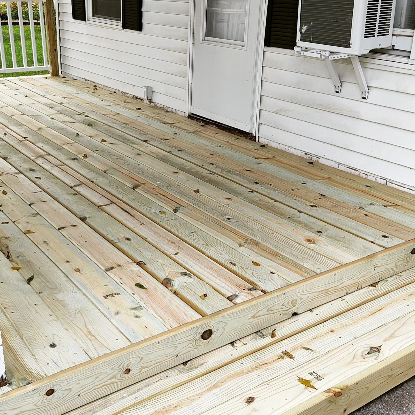 A wooden deck is sitting in front of a white house.