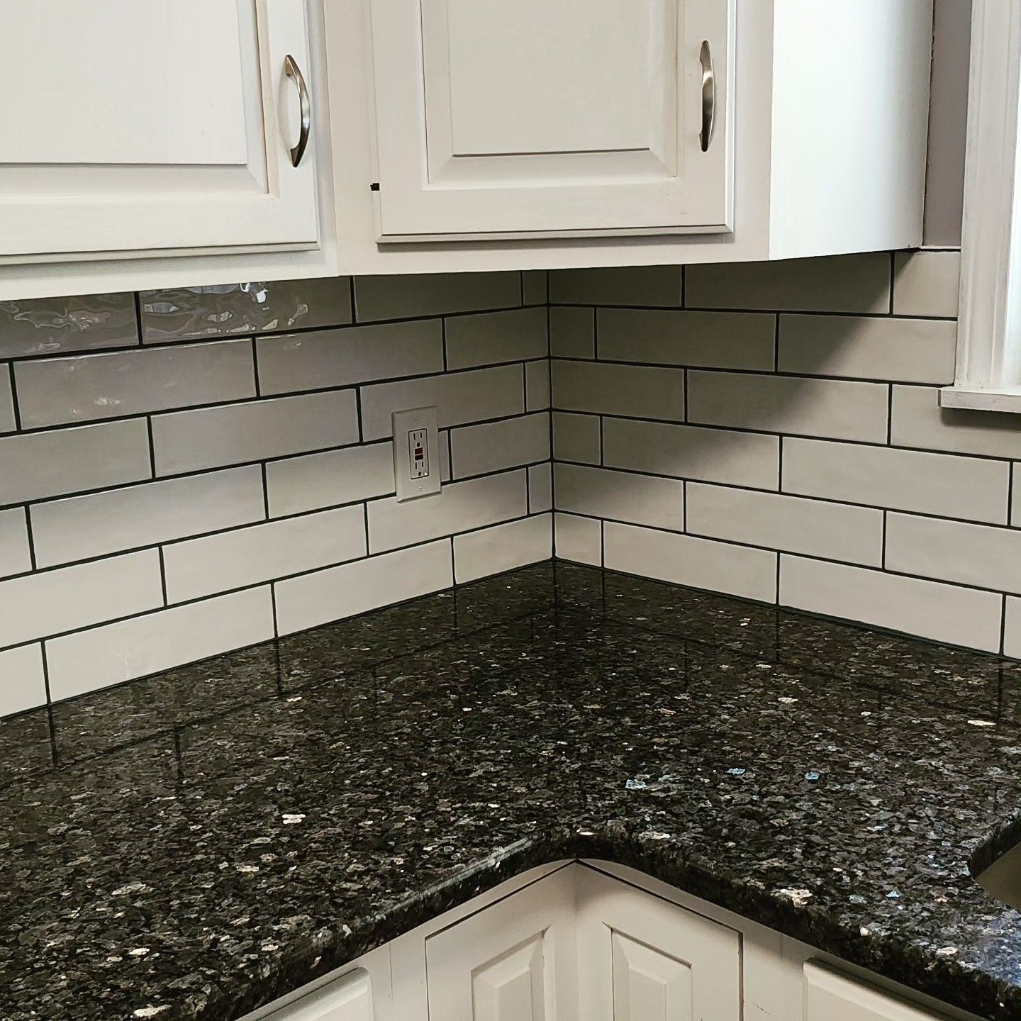 A kitchen with black granite counter tops and white cabinets