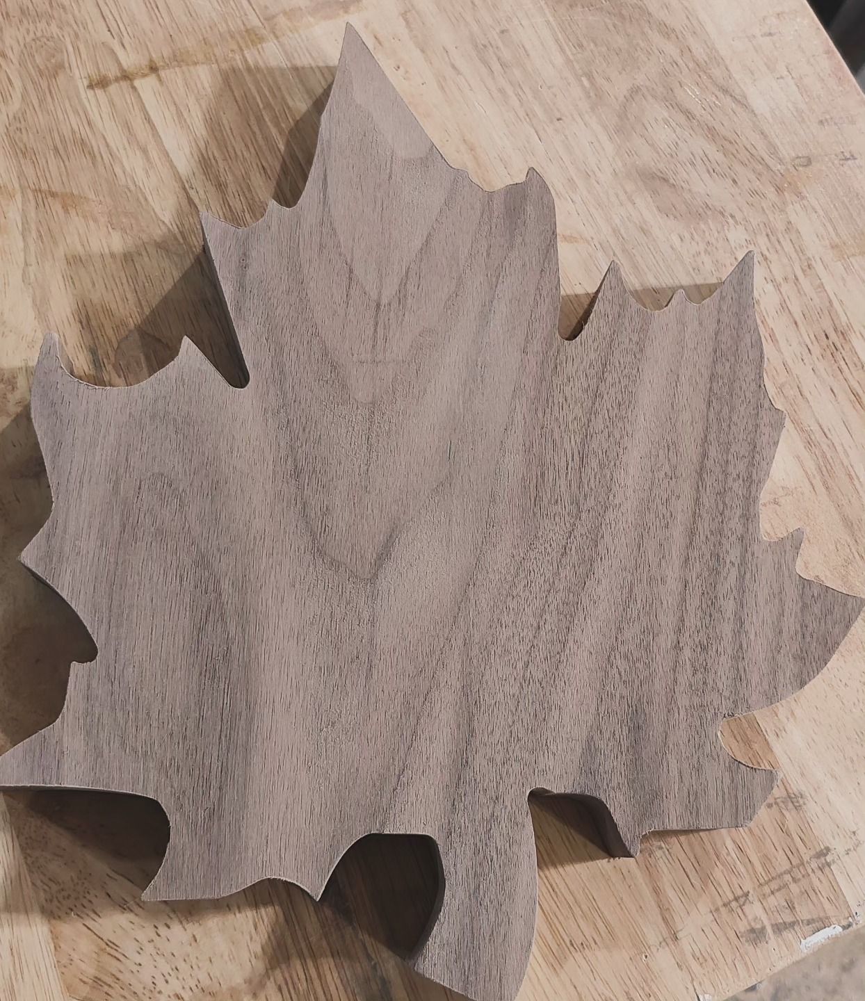 A wooden leaf is sitting on a wooden table.