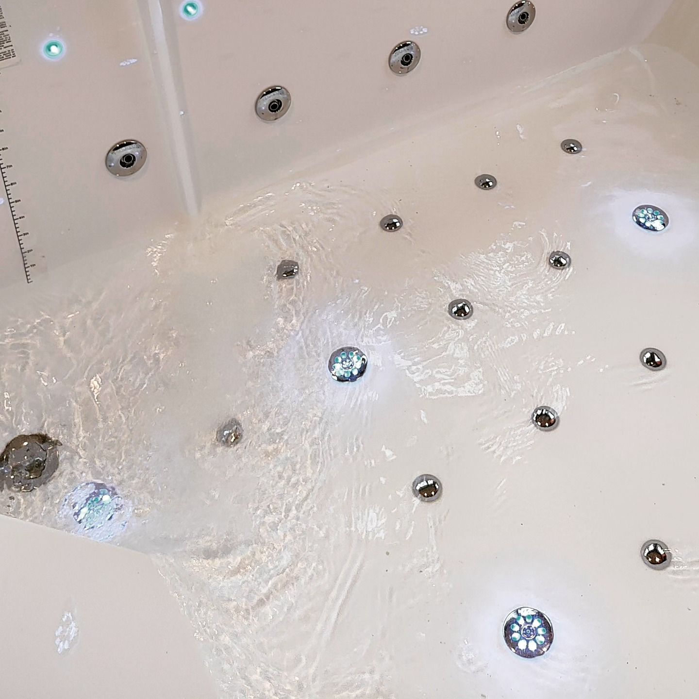 A white bathtub with a lot of jets and lights on it.
