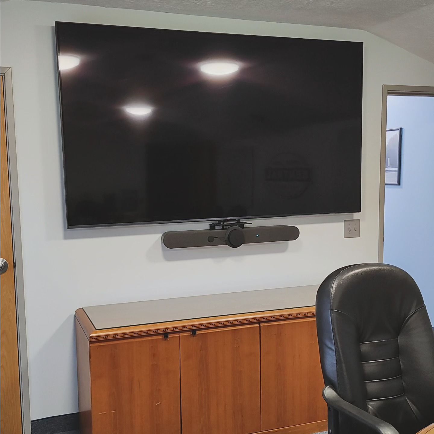 A large flat screen tv is mounted on a wall above a wooden cabinet