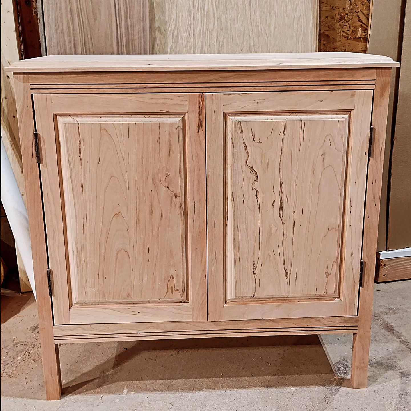 A wooden cabinet with two doors is sitting on the floor
