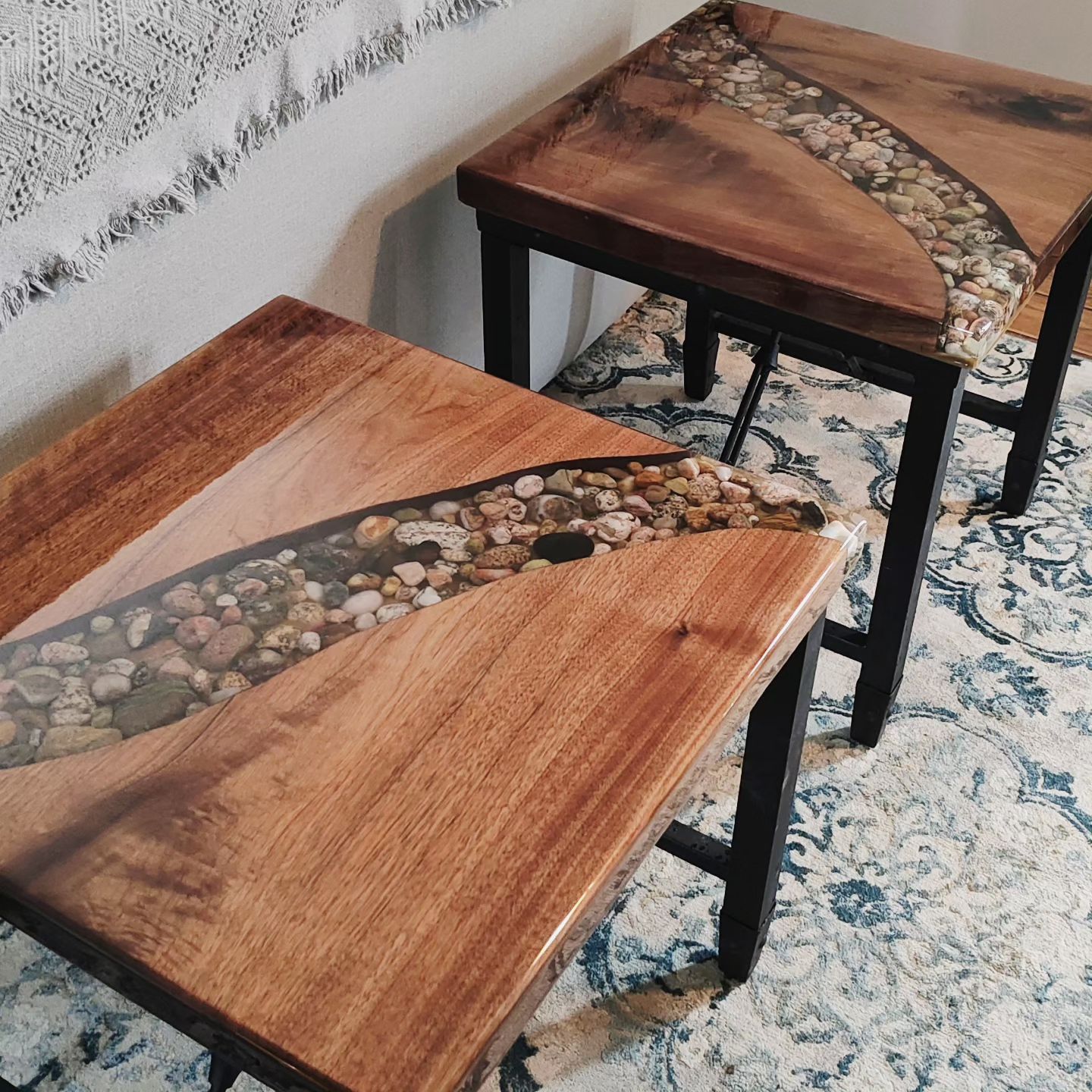 Two wooden tables with rocks on them are sitting on a rug.