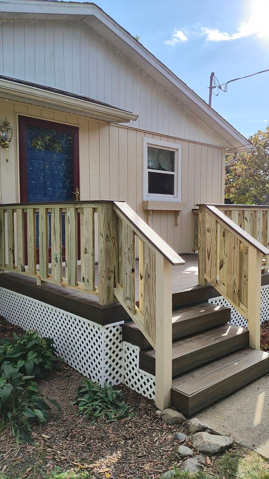 A white house with a wooden porch and stairs leading up to it.
