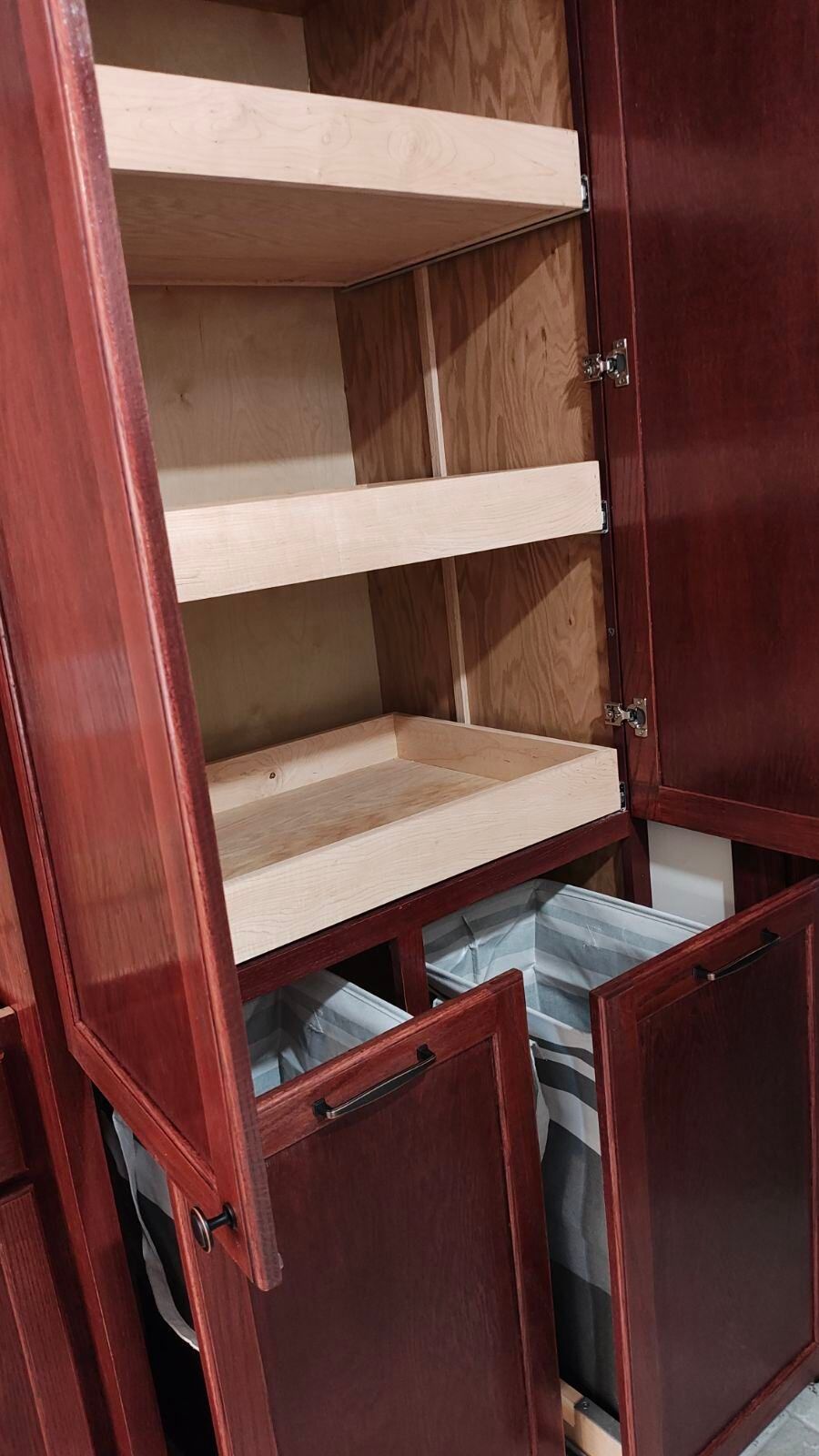 The inside of a wooden cabinet with the doors open and shelves.