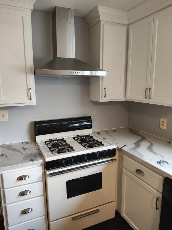 A kitchen with a stove and a hood above it
