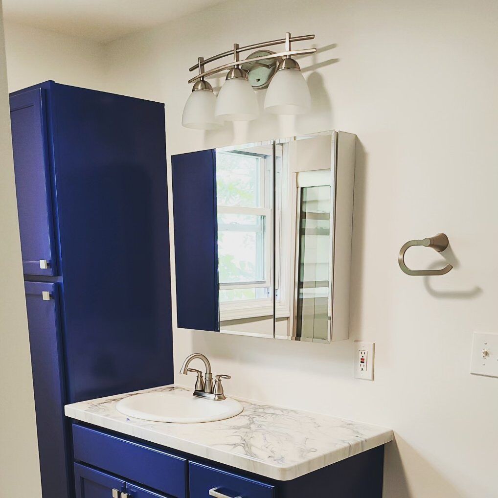A bathroom with blue cabinets a sink and a mirror