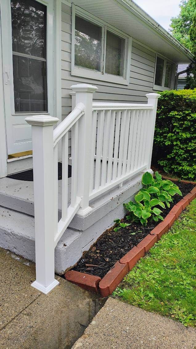 A white railing is sitting on the sidewalk in front of a house.