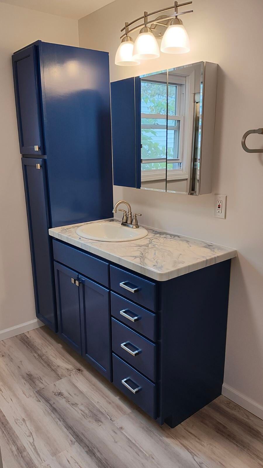 A bathroom with blue cabinets , a sink , and a mirror.