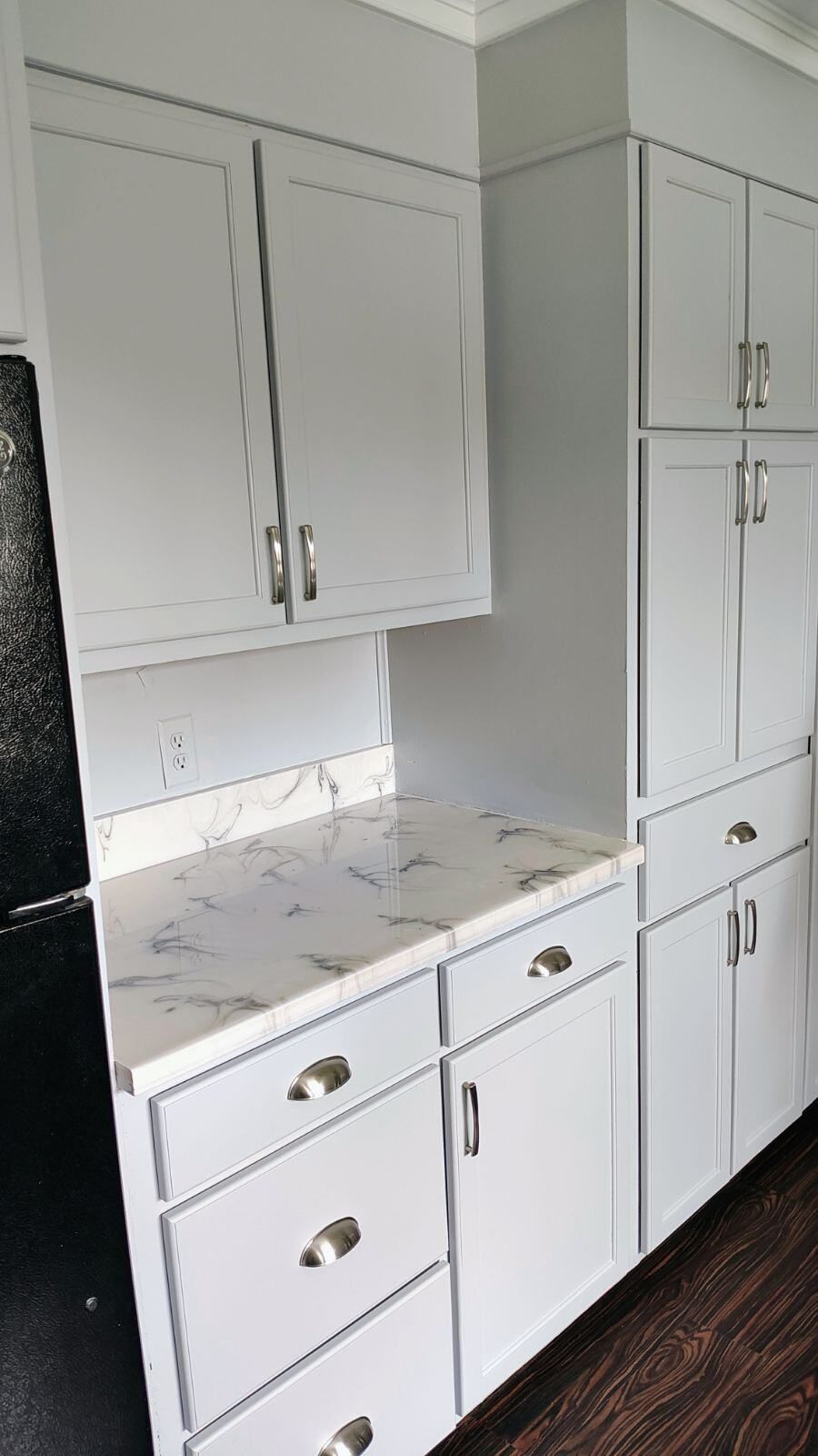 A kitchen with white cabinets and marble counter tops.