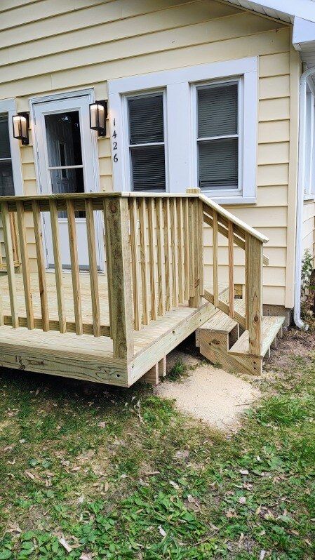 A wooden deck with stairs is in front of a house.