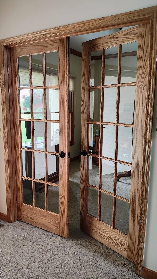 A pair of wooden french doors are open in a living room.