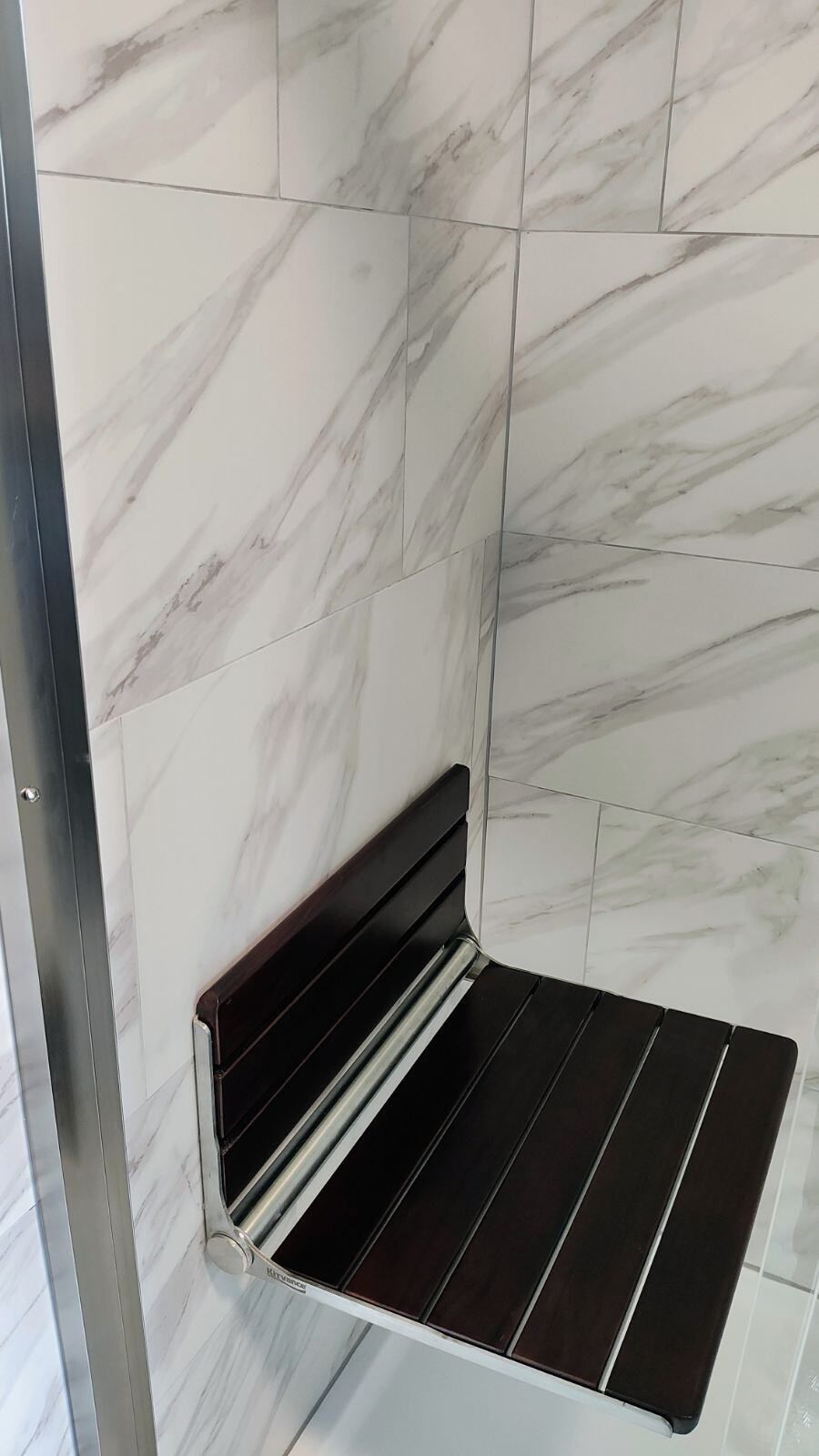 A wooden seat is sitting in the corner of a shower.