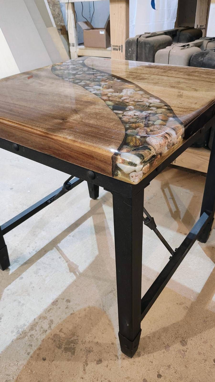 A wooden table with a resin top is sitting on a tiled floor.