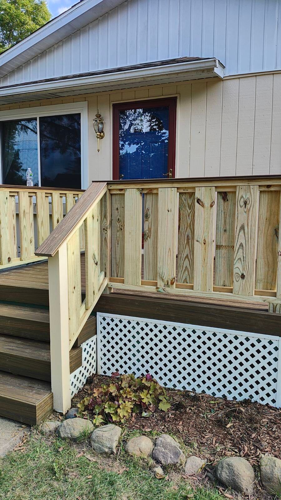 A mobile home with a wooden deck and stairs.