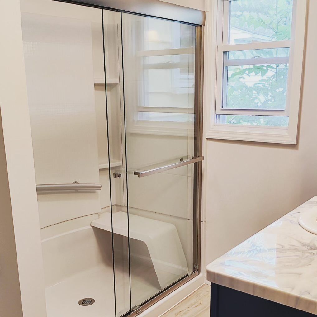 A bathroom with a sliding glass shower door and a bathtub.