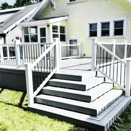 A yellow house with a white deck and stairs