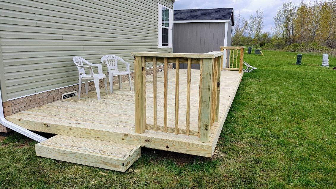 A wooden deck with chairs and a table in front of a house.