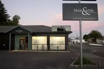 A black and white sign is in front of a building.