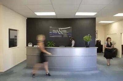 Two women are standing in front of a reception desk in an office.