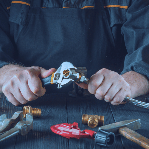A man is working on a pipe with a wrench.