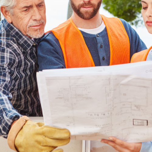 A man in an orange vest is looking at a blueprint