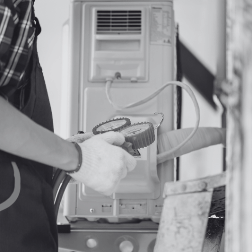 A black and white photo of a man working on an air conditioner