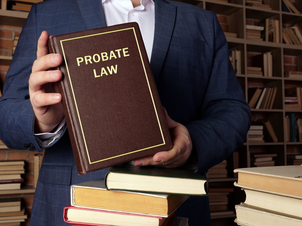 A Man in a Suit is Holding a Book Titled Probate Law — Morris Legal & Conveyancing in Forster, NSW