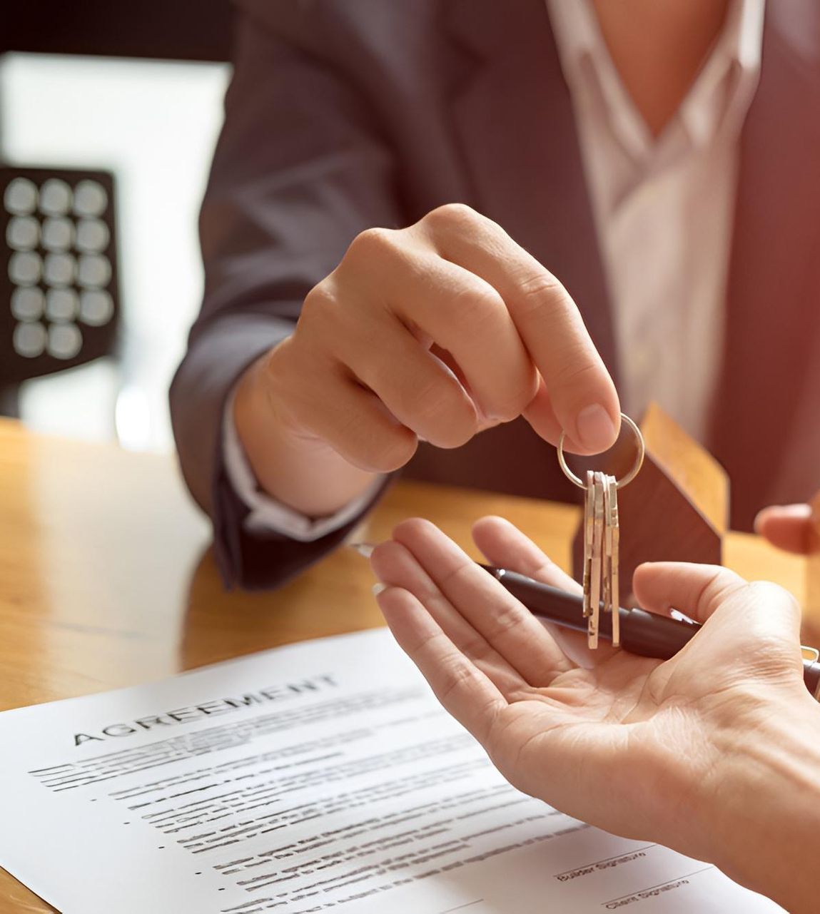 Person Handing Keys to Another Person Over a Contract, Possibly a Real Estate Deal — Morris Legal & Conveyancing in Forster, NSW
