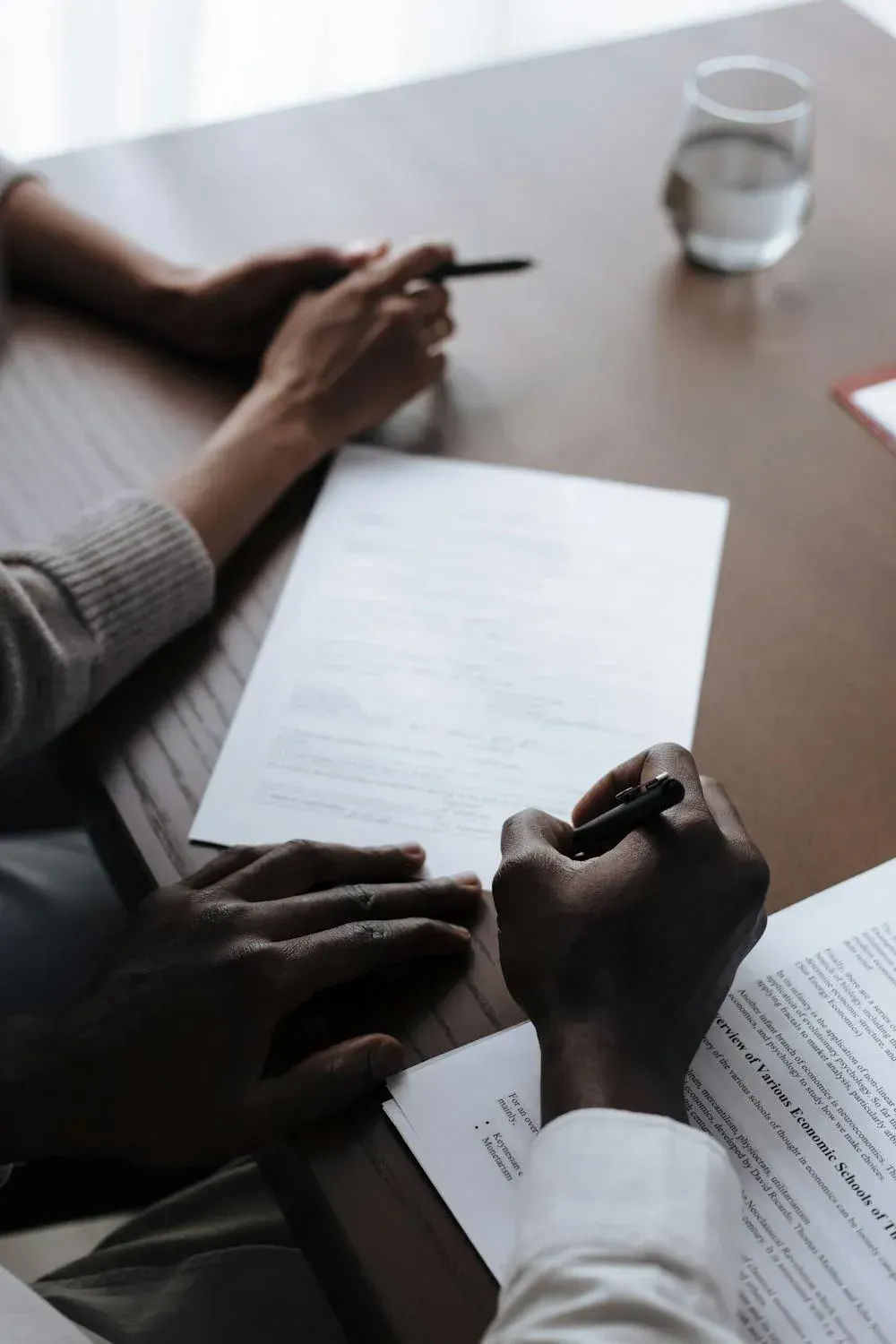 A man and a woman are sitting at a table signing a document.