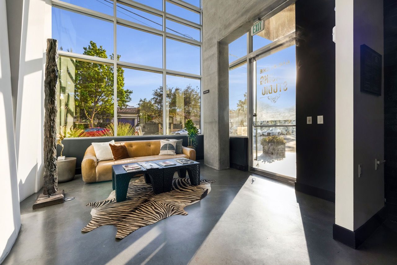 Angelene Apartments Modern apartment lobby with large windows, a tan sofa, coffee table, and zebra rug.