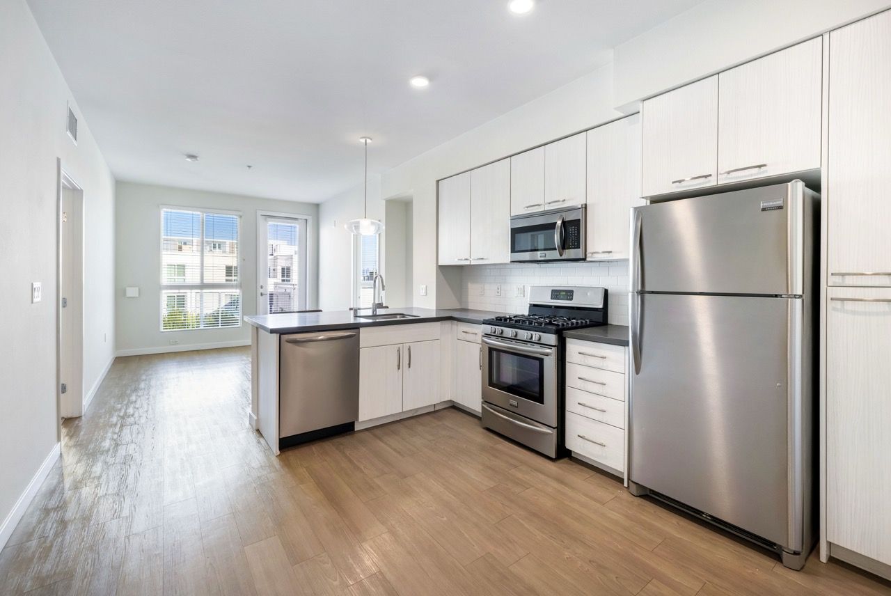 Angelene Apartments Bright kitchen with white cabinetry, stainless steel appliances, and an island.