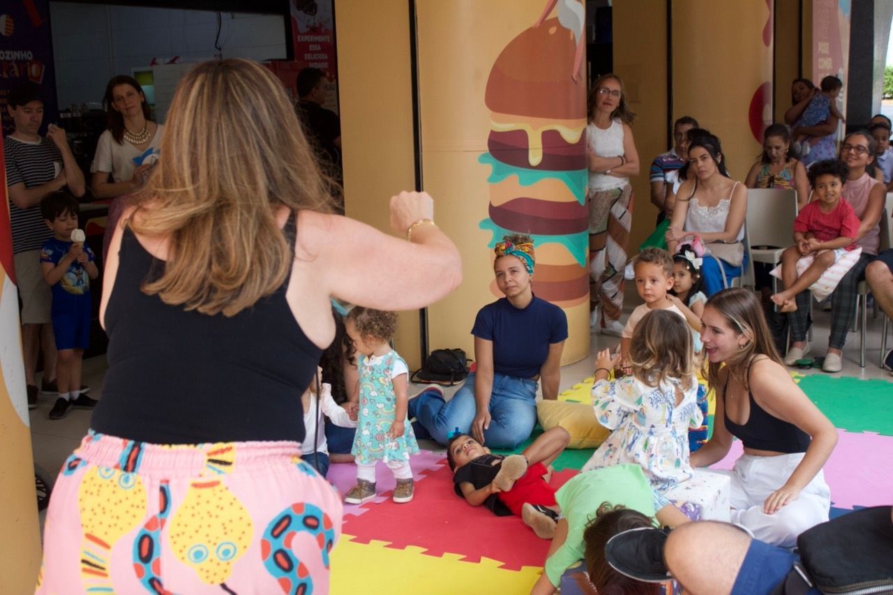 Crianças e adultos vendo contação de histórias.