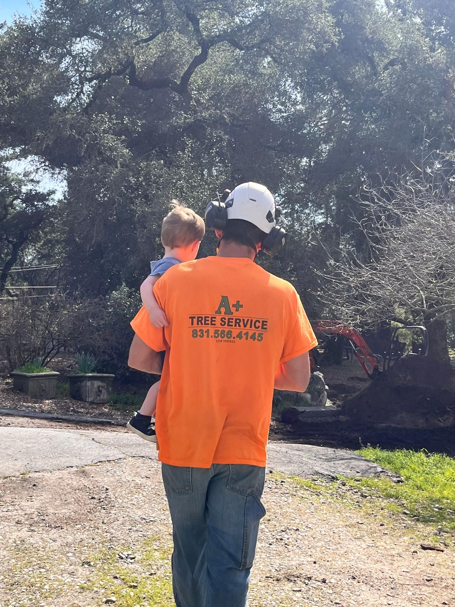 A man in an orange shirt is holding a baby in his arms.