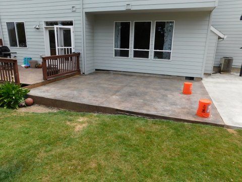 A backyard with a patio and a house in the background.