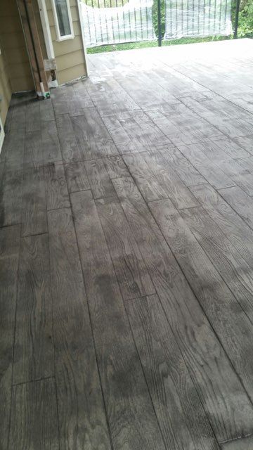 A patio with a wooden floor and a fence in the background.