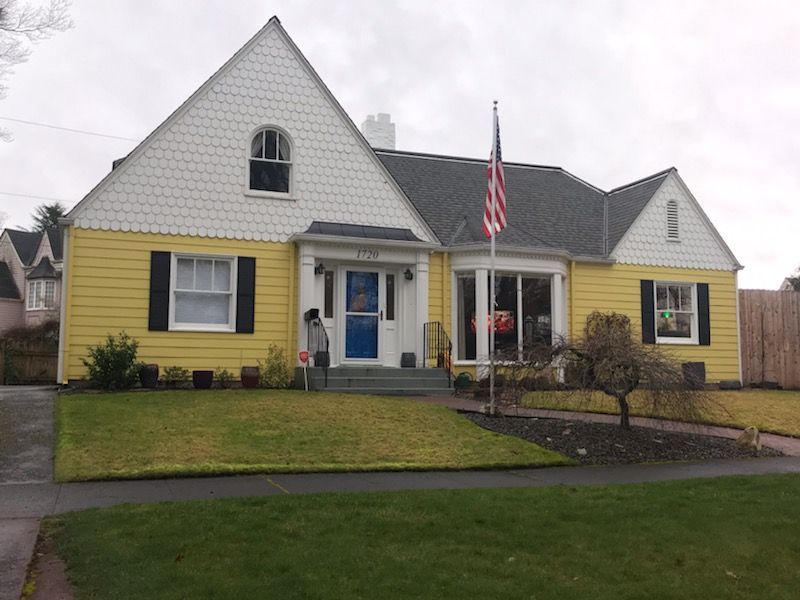 A yellow and white house with a blue door and black shutters