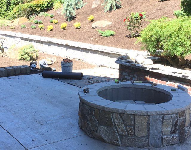 A stone fire pit is being built on a patio