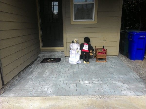 Two halloween decorations are sitting on a patio in front of a house.