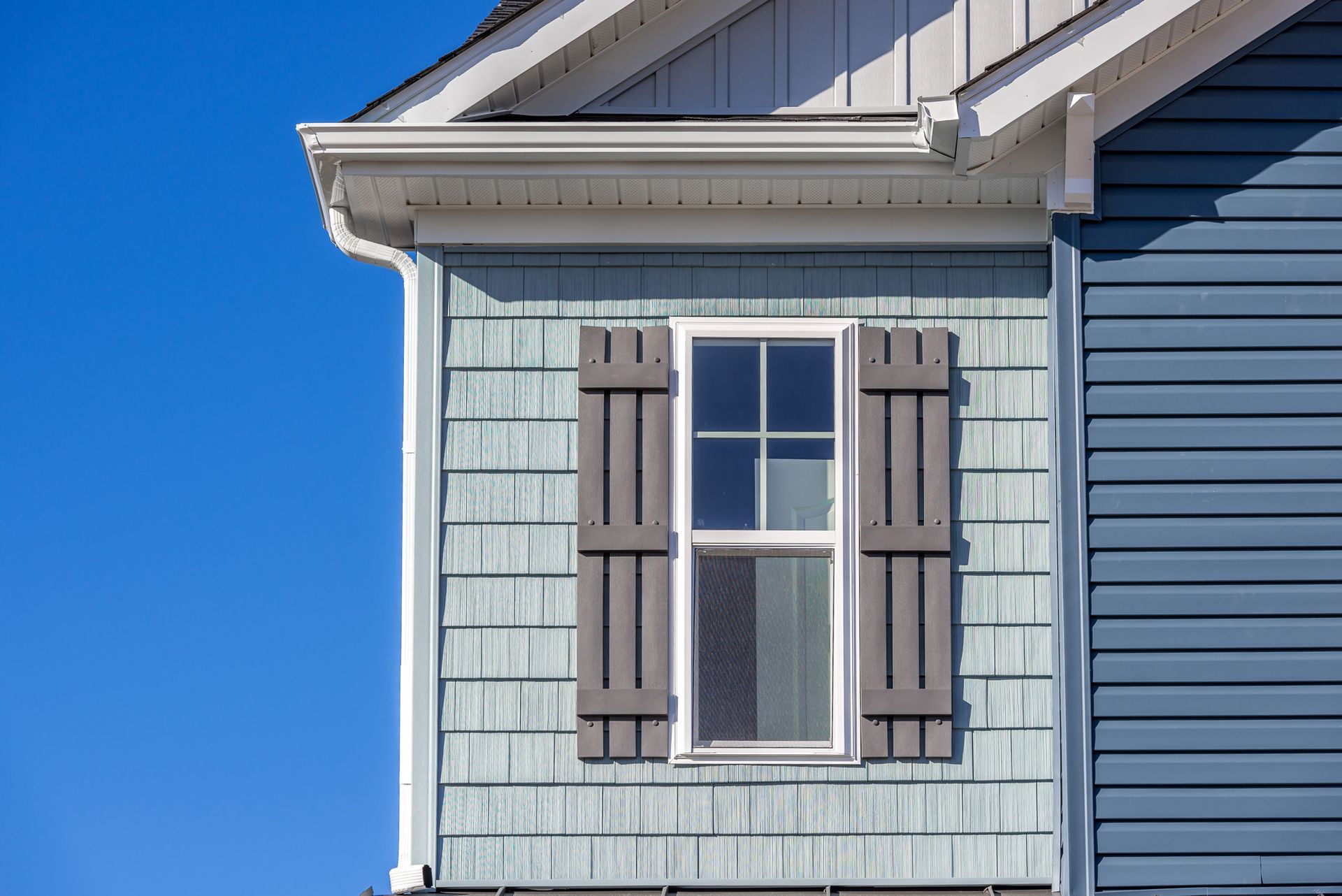 The side of a house with a window and shutters on it.