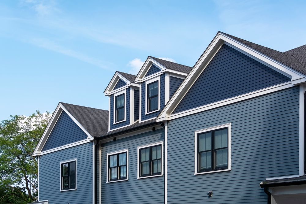 A large blue house with a gray roof and a lot of windows.