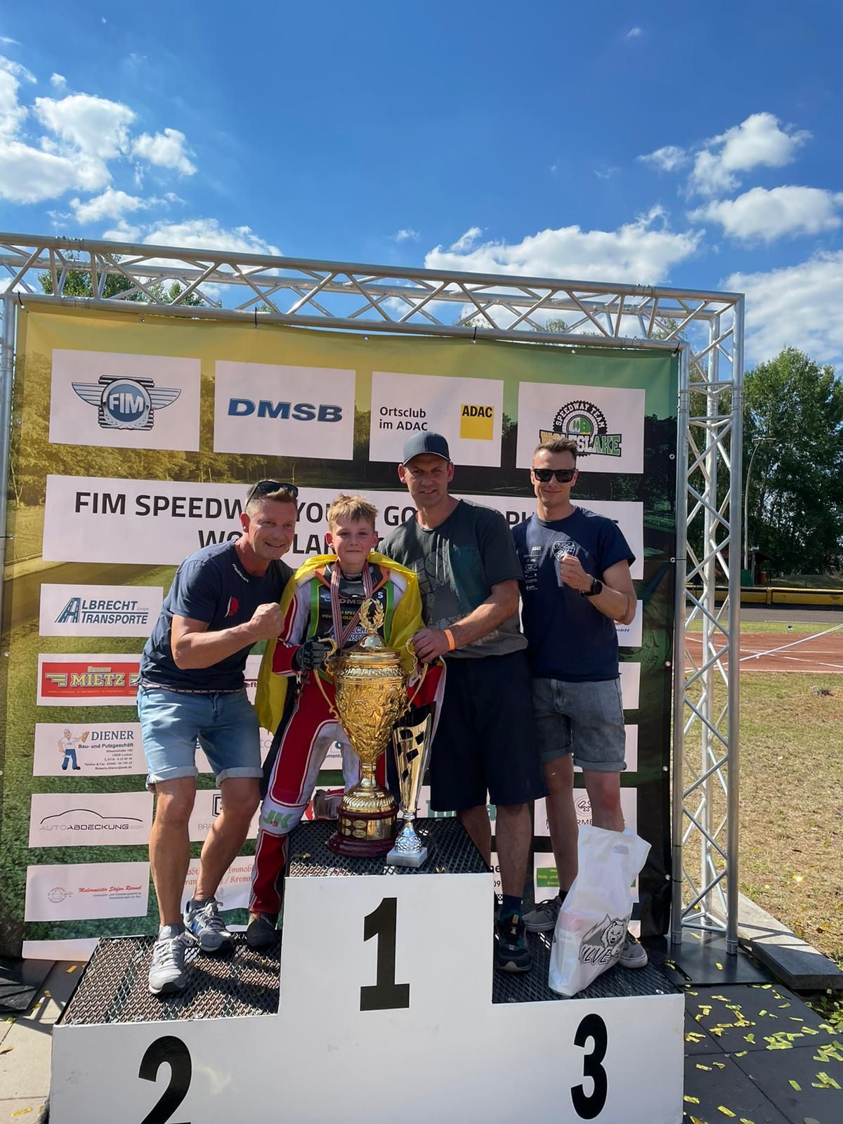 Eine Gruppe Männer steht auf einem Podium und hält eine Trophäe in den Händen.