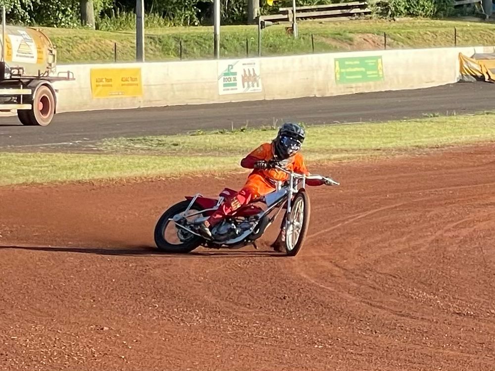 Eine Person fährt mit einem Motorrad auf einem Feldweg.