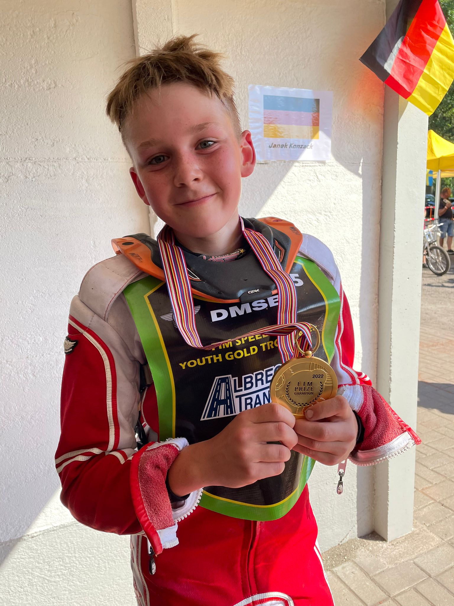 Ein kleiner Junge hält eine Goldmedaille um den Hals.