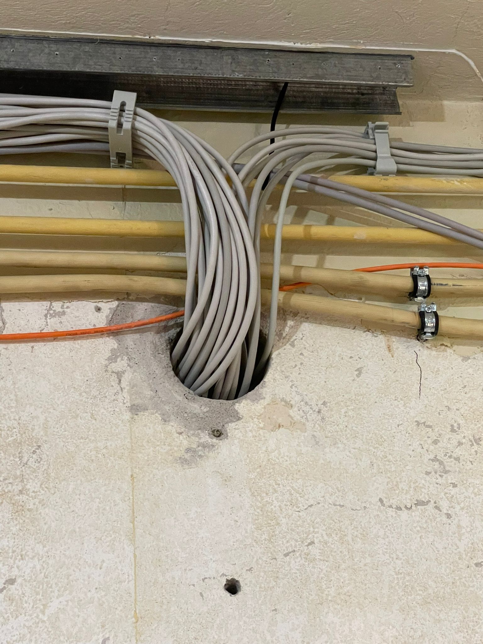 Aus einem Loch in der Wand kommen viele Kabel.