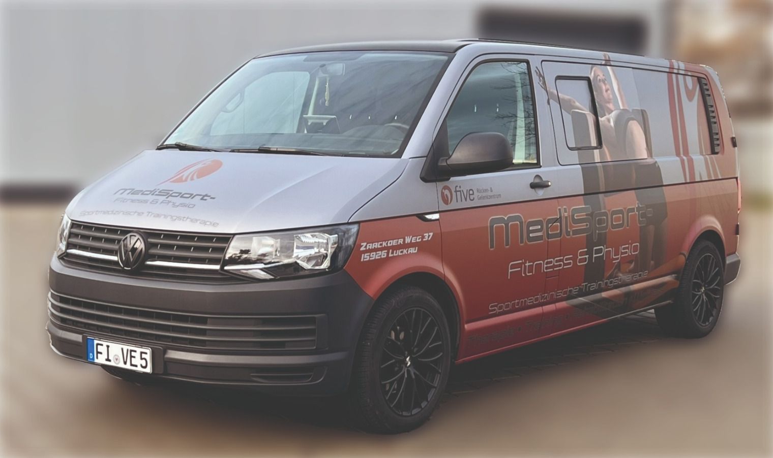 Ein rot-grauer Lieferwagen steht vor einem Gebäude.